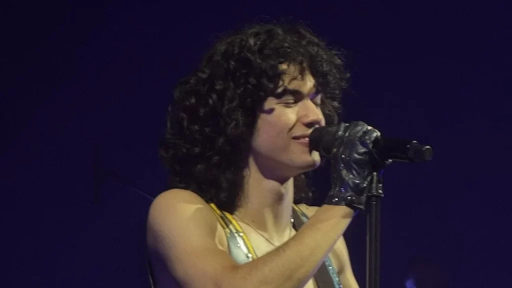 Conan Gray singing during the Wishbone tour, with vibrant stage lighting and themed set design matching the album’s artwork.