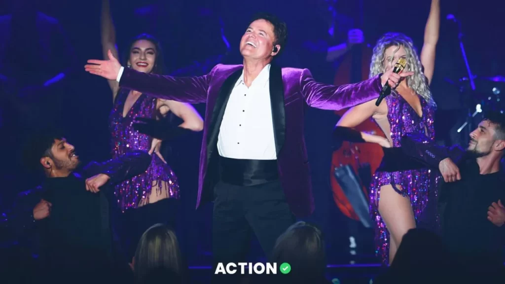 Bright colorful stage lights shining behind Donny Osmond during his Las Vegas 2025 concert.