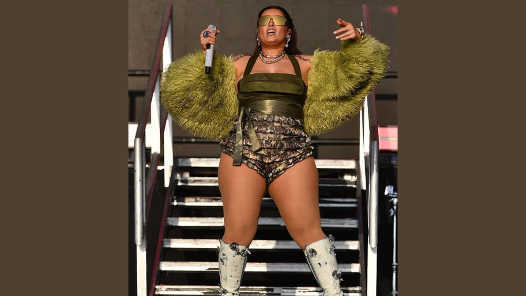Canadian singer Nelly Furtado singing at an outdoor music festival in 2025, wearing a colorful outfit and engaging with the audience.