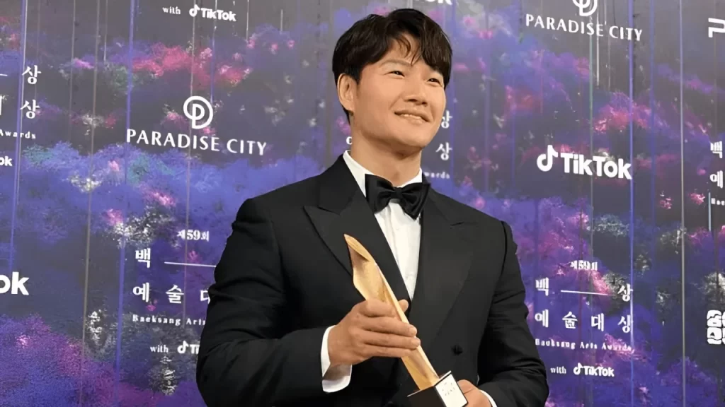 Kim Jong Kook in a smart casual outfit during a press event, symbolizing his milestone announcement.