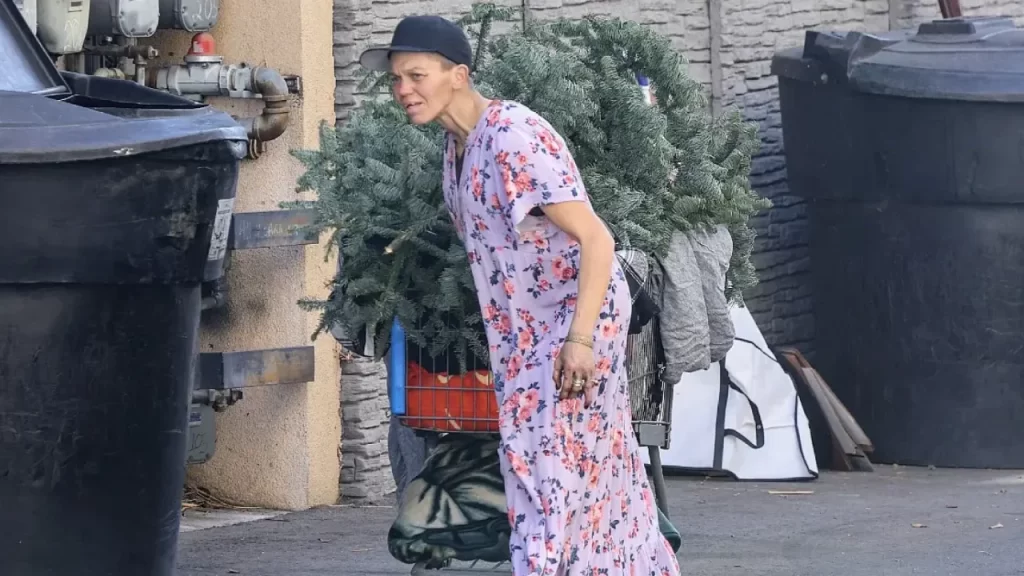 A closer shot of Loni Willison amid street life, emphasizing her thin frame and worn attire.