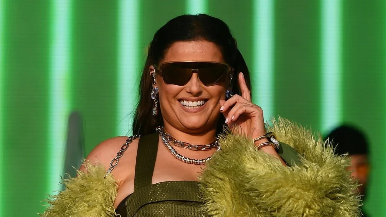 Nelly Furtado performing live on stage at a summer music festival in Europe, with vibrant stage lights and a cheering crowd in the background.