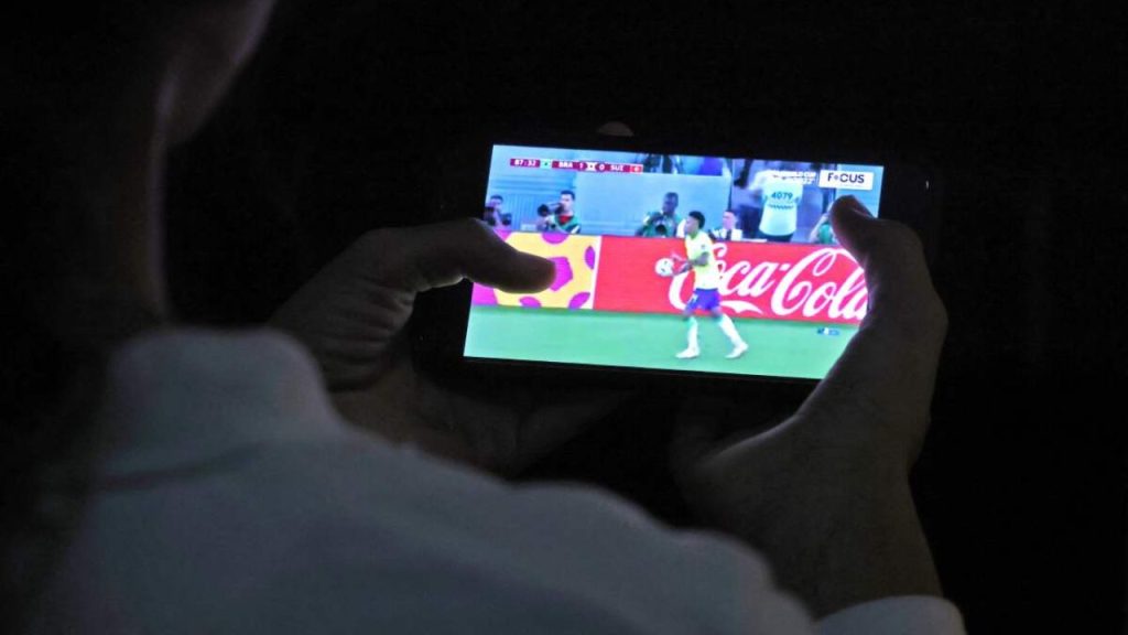 Person watching a live soccer match on a mobile device, symbolizing disrupted streaming habits after Streameast shutdown.