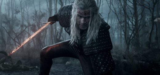 Liam Hemsworth wearing Geralt’s signature medallion and fantasy armor in a dim, misty landscape