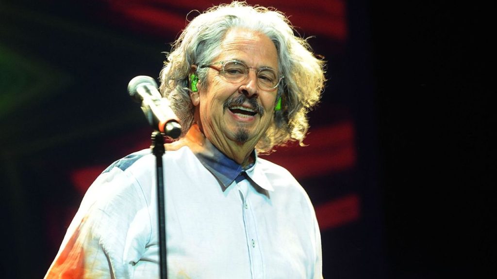 Up-close of Mark Volman singing with a big grin, embodying warmth and optimism even in later years