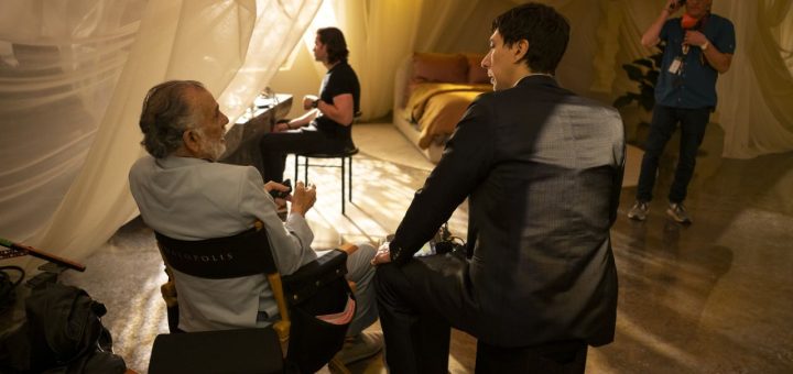 Actor seated on set surrounded by crew in dim lighting during Megalopolis production
