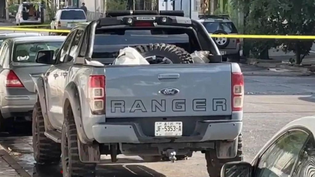 A gray Ford pickup truck cordoned off at a crime scene with yellow police tape—site where Esmeralda Ferrer Garibay and her family were discovered wrapped in plastic inside the vehicle.