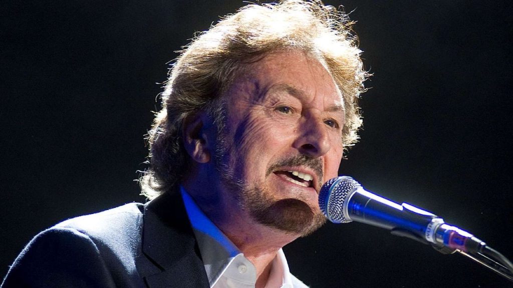 Rick Davies singing and playing keyboards on stage at the O2 Arena in London, captured during a live performance.